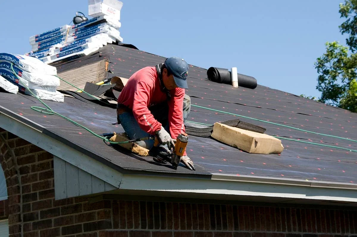 Roofing contractor in Santa Rosa, California installing underlayment and shingles on a residential roof using a nail gun for professional roof repair and installation.