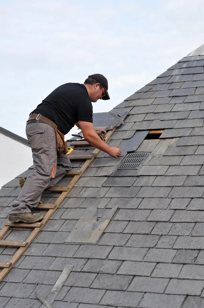 Professional roofing contractor installing slate tiles and roof vent on residential home in Napa California