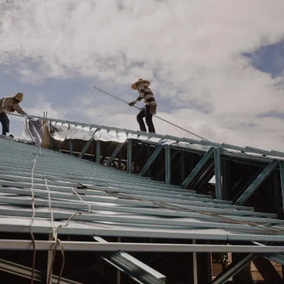 Low angle view of men working on rooftop against sky